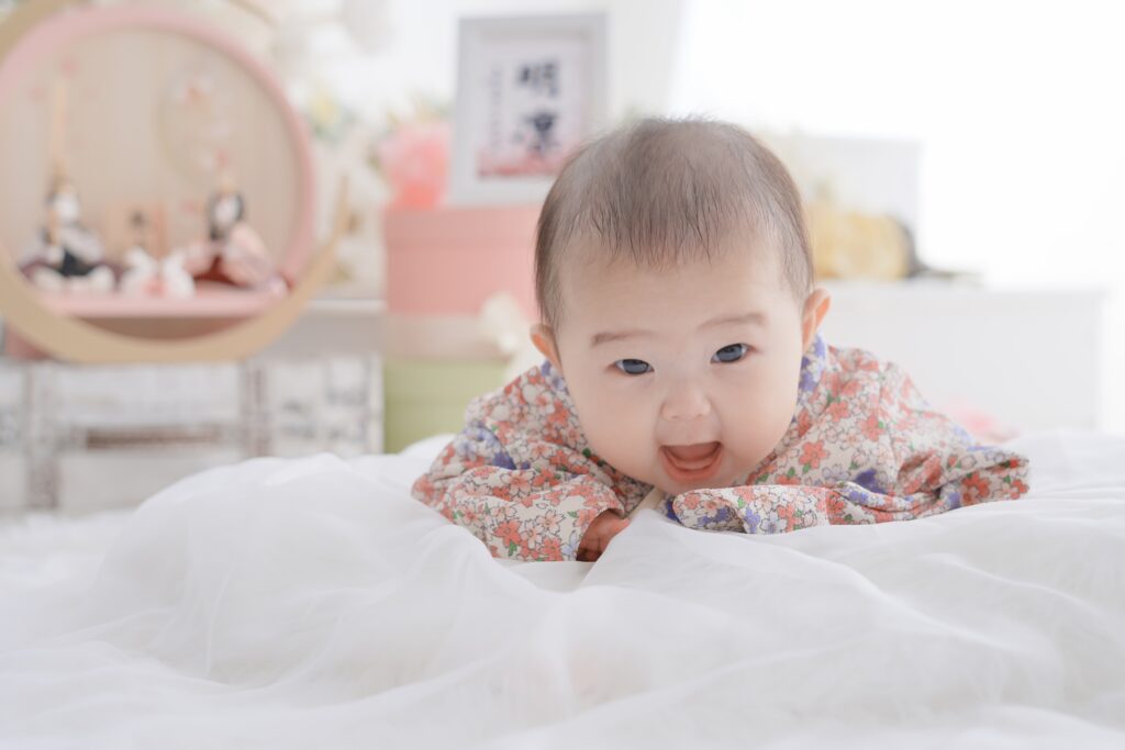 初節句フォト撮影で和服を着た赤ちゃんがうつ伏せになり笑顔を見せている様子